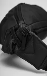 Riñonera negra confeccionada en cordura impermeable de alta resistencia. Presenta tres compartimentos principales con cierres metálicos, un bolsillo lateral adicional y una correa ajustable de alta densidad con broche de seguridad. Incluye una chapa metálica decorativa en el frente.
