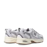Championes New Balance 530 de mujer, color gris claro con detalles en blanco y beige. Confeccionados en malla y gamuza, con el logo "N" en los laterales y suela de goma.