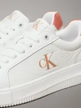 Zapatillas urbanas Calvin Klein de cuero blanco con logo CK en el lateral y detalle de gamuza color salmón en el talón.