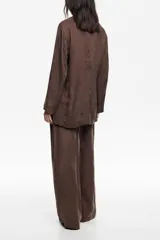 Chaqueta de corte cruzado color marrón, con cuello de solapa, cierre mediante lazo en la cintura y bolsillos de plastrón frontales.