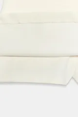 Falda pantalón de tiro bajo color blanco crudo, con diseño de cintura asimétrica y cierre lateral con cremallera oculta en costura.