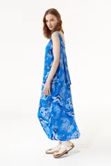 Vestido largo azul con estampado de estrellas de mar y flores. Tiene breteles finos regulables, cuello redondo y espalda descubierta.