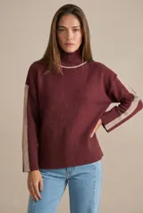 Sweater de punto con cuello alto, diseño oversize y mangas largas. Presenta un contraste de color en el cuello y una franja vertical en las mangas en tono beige.