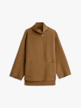Abrigo de corte oversize confeccionado en mezcla de lana de doble cara, color marrón. Presenta cuello chimenea, cierre frontal con un botón visible y otro oculto, y dos bolsillos delanteros de parche.