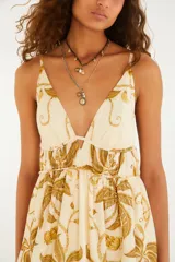 Vestido largo blanco de tirantes finos con estampado botánico en tonos mostaza y beige, escote en V profundo y falda amplia con vuelo.