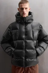 Campera puffer negra con capucha ajustable, cierre frontal con cremallera, bolsillos laterales con cremallera oculta y relleno de plumón y pluma.