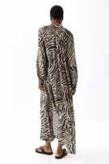 Vestido túnica largo de mezcla de viscosa con estampado de cebra, diseño oversized, cuello elevado con frunces, escote en V y mangas globo largas con puños elásticos. Incluye un cinturón fino para atar con borlas y tajos laterales.