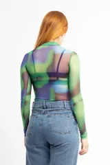 Remera de mesh transparente con cuello alto y estampado abstracto en tonos verde, azul y violeta.