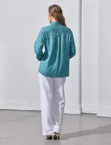 Camisa color verde oliva de lyocell, marca Cyrus. Tiene cuello con solapa, abertura central con botones, mangas 3/4 regulables con presilla y botón, y dos bolsillos delanteros aplicados.