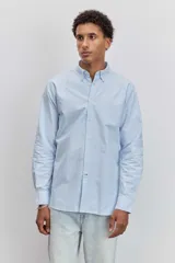 Camisa de manga larga en color celeste con estampado de rayas verticales finas, cuello abotonado y cierre frontal con botones.