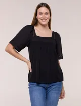 Blusa holgada de color negro, confeccionada en mezcla de modal y algodón, con escote cuadrado y mangas cortas amplias adornadas con detalles de puntilla calada. Presenta un canesú fruncido en el frente que aporta movimiento y un diseño de largo a la cadera.