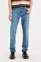 Jean de corte slim fit con tiro medio, confeccionado en denim de tono azul medio con acabado desgastado.
