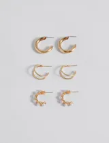 Set de tres pares de aros dorados con cierre de poste. Incluye un par de aros gruesos, un par de aros dobles y un par de aros con detalle de perlas.