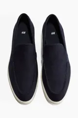 Mocasines de gamuza azul marino con costura tradicional en la parte frontal y suela de goma blanca.