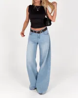 Pantalón jean de corte wide leg en tono celeste claro, de tiro medio con presillas y cierre frontal con botón y cremallera. Presenta diseño amplio en las piernas.