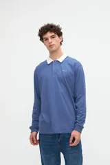 Remera polo de manga larga azul con cuello camisero blanco y cierre frontal de botones ocultos. Presenta un pequeño bordado con el texto "uniform" en el pecho y calce relajado.