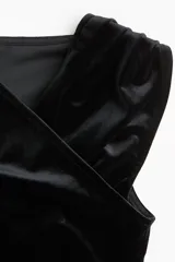 Top sin mangas de velour negro, ajustado al cuerpo, con escote cruzado drapeado y frunces laterales.
