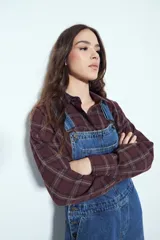 Camisa tipo leñadora de corte oversize, con estampado de cuadros en tonos negro y marrón. Presenta cuello clásico, cierre frontal con botones y mangas largas con puños abotonados.