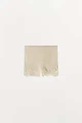 Shorts tipo lencero de tiro medio, confeccionado en tejido satinado con cintura elástica y detalle de aplicación de encaje a tono en el ruedo.