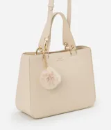 Cartera satchel mediana color beige, con cierre de cremallera, correa de mano y bretel largo desmontable. Incluye un llavero de pompón de piel sintética.