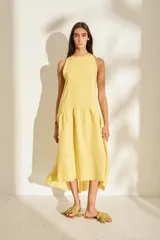 Vestido midi de lino color amarillo, sin mangas, con escote redondo y corte fluido con volados en la parte inferior.