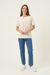 Remera de manga corta color beige, confeccionada en 100% algodón, con cuello redondo y estampa frontal con texto en tonos rosados.