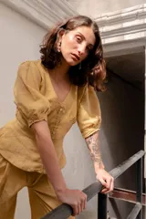 Camisa color mostaza de lino con corte en la cintura y abotonadura central. Tiene manga abullonada con detalle de elástico en puños.