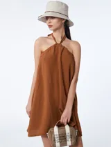 Vestido corto azul marino de tencel con corte evasé, cuello halter con lazo ajustable y espalda descubierta.