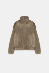 Cazadora biker de cuero con acabado de gamuza color marrón, cuello alto envolvente, cierre frontal cruzado con botones y cremallera, bolsillos ribeteados y bajo con elástico fruncido.