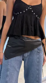 Bandana de cintura en cuero sintético negro con forma triangular, diseñada para anudar en el lateral con tiras finas.