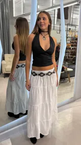 Pollera larga blanca de tiro bajo, confeccionada en tejido liviano con diseño de paneles escalonados y silueta amplia.
