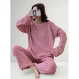 Conjunto de pijama de dos piezas confeccionado en tela de plush texturizada con diseño de rayas verticales en relieve. Incluye una remera de manga larga con cuello redondo y un pantalón de corte holgado. La remera presenta un pequeño bordado decorativo en el pecho.