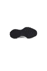 Zapatilla deportiva de estilo retro, con capellada combinada de gamuza gris y paneles textiles grises. Presenta cordones blancos y una suela gruesa blanca con detalles en negro y toques de color en la parte inferior.
