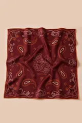 Pañuelo cuadrado de seda color bordó con estampado de estilo paisley y rosas en líneas blancas y naranjas. Presenta bordes en tono naranja y detalles de terminación hechos a mano.