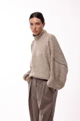 Sweater de punto grueso con cuello alto, diseño de hombros caídos y mangas amplias con puños acanalados.