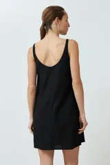 Vestido corto negro de lino, corte recto, sin mangas y con bolsillos laterales.