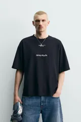 Remera de corte holgado confeccionada en algodón con interior de tejido rizo. Presenta cuello redondo, manga corta y estampados con texto en contraste en la parte frontal.