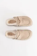 Zueco de gamuza color beige con interior forrado en piel sintética, suela de corcho y base de goma negra.