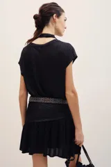 Falda corta de corte cruzado con volados en el borde inferior, confeccionada en tejido metalizado dorado.