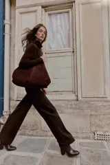 Pantalón recto color marrón oscuro, de tiro medio, con cintura elástica en la espalda, bolsillos delanteros de vivo y cierre frontal con cremallera, botón interior y gancho.