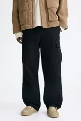Pantalón cargo de lona de algodón con bolsillos laterales con solapa, bolsillos al bies y bolsillos traseros. Presenta pliegues en las rodillas y cierre con botón.
