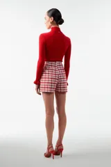 Buzo de punto rojo con cuello alto y mangas largas con volados en los puños.