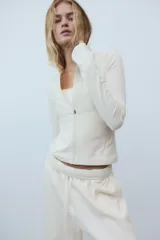 Campera deportiva de corte ajustado confeccionada en tejido funcional SoftMove y DryMove. Presenta capucha, cierre frontal con protección para el mentón, bolsillos laterales con cierre y mangas extralargas con abertura para el pulgar.