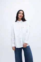 Camisa blanca de algodón con cuello solapa clásico, bolsillo cuadrado en el pecho, botones personalizados y calce relaxed.