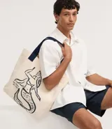 Bolsa de tela color beige con estampado de sirena en azul marino y asas reforzadas del mismo color.