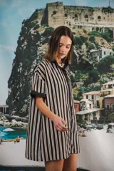 Vestido camisero corto, con cuello mao, botones a tono y parche con logo en el frente. Diseño a rayas verticales negras y blancas.