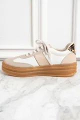 Zapatillas bajas de cuero color blanco y beige con suela marrón y detalle animal print en el talón.