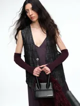 Chaleco sastrero de denim negro con diseño de cuadros y aplicación de lentejuelas sutiles. Presenta escote en V, cierre frontal con botones metálicos y bolsillos delanteros.