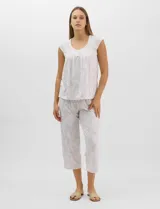 Pijama compuesto por remera sin mangas con escote redondo, botones frontales y detalle de puntilla, acompañado de un pantalón capri con cintura elástica. Presenta un estampado floral en tonos rosados sobre base gris.