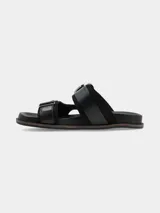 Sandalia de cuero negro de estilo boho con dos tiras anchas, hebillas grandes metálicas y herrajes plateados, con base cómoda.